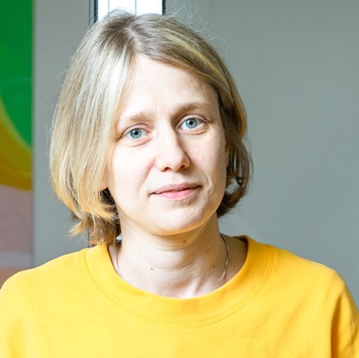 SchoolioWP komandas dalībniece — sieviete ar īsiem gaišiem matiem dzeltenā džemperī